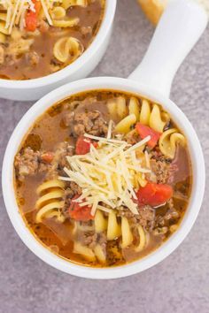 two white bowls filled with pasta and meat soup on top of a gray countertop