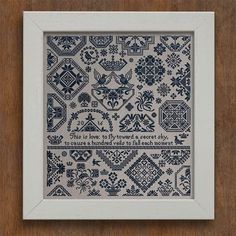 a blue and white cross stitch pattern in a frame on a wooden surface with the words,