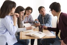 a group of people sitting around a table with an open book in front of them