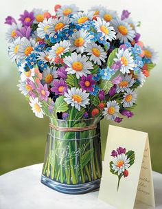 a vase filled with lots of colorful flowers next to a card