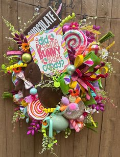 a wreath made out of candy and lollipops is hanging on a fence