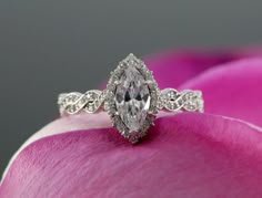 a close up view of a diamond ring on top of a pink tulip flower