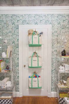 three bags are hanging on the wall in front of a white door with green trim