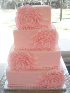 a three tiered cake with pink frosting roses