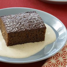 a piece of chocolate cake on a blue plate with white sauce and fork next to it