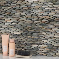 two bottles sitting on top of a counter next to a wall made out of rocks