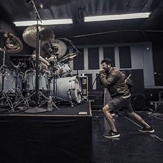 a man standing on top of a stage next to drums