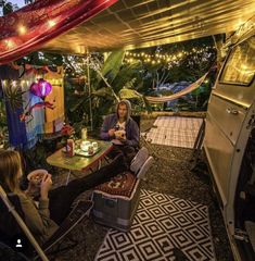 two people sitting at a table under a tent with lights strung from the ceiling above them