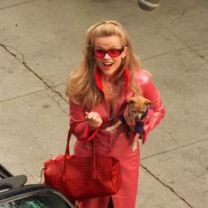 a woman in red carrying a small dog