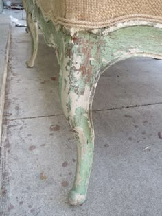 an old green bench sitting on the sidewalk