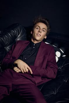 a man in a purple suit sitting on a black couch