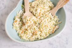 a bowl filled with coleslaw and two wooden spoons