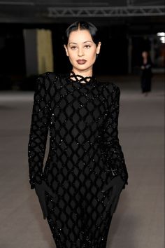 a woman walking down a runway in a black dress