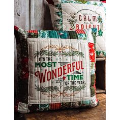 two decorative pillows sitting on top of a wooden table next to each other, one with the words it's the most wonderful time of the year