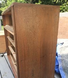 an old wooden cabinet sitting on top of a table next to a blue tarp