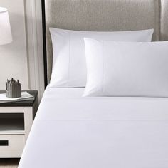 a bed with white sheets and pillows in a hotel room or motel bedroom, close up