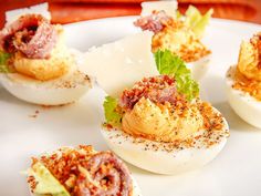 deviled eggs with meat and vegetables on a white plate