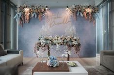 a living room filled with furniture and flowers on top of a table in front of a blue wall