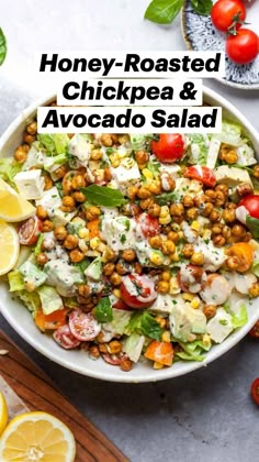 a salad with tomatoes, lettuce and chickpeas in a white bowl