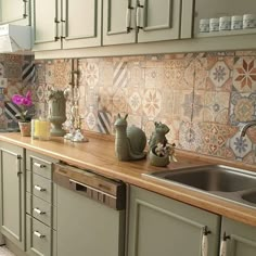 a kitchen with green cabinets and tile backsplashes on the counter top, along with a sink and dishwasher