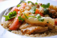 a white plate topped with meat and veggies on top of brown grits