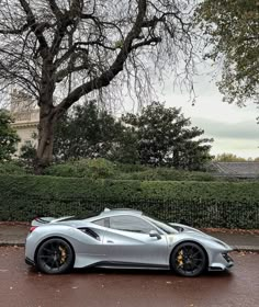 a silver sports car parked in front of a tree