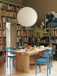 a dining room table with chairs and bookshelves in front of it, next to a bookcase full of books