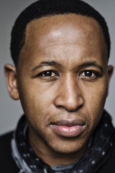 a close up of a person with a scarf around his neck and wearing a black jacket