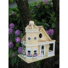 a yellow bird house hanging from a tree