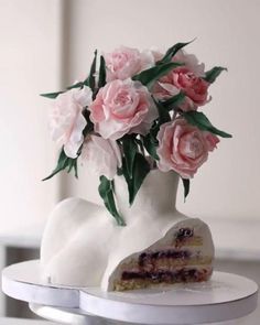 there is a cake with flowers in the vase on top of it and one slice has been taken out