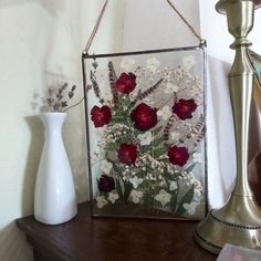 a vase with some flowers in it next to a mirror on a wooden table near a lamp