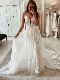 a woman taking a selfie while wearing a wedding dress in front of a mirror