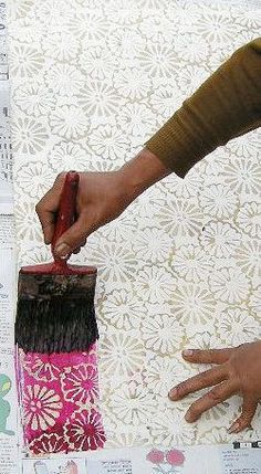 a person using a brush to paint a vase