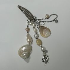 a close up of a piece of jewelry on a white surface with beads and chains