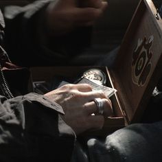 a man is holding a watch in his hand and looking at the box with it