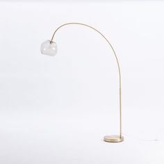 a floor lamp with a glass ball on the top and a gold metal base, against a white background