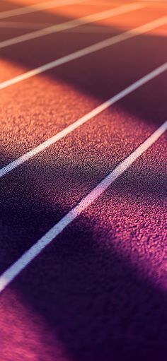 an image of a running track with the sun shining on it and shadows coming from behind