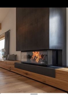 a living room with a fire place in the center and wood flooring on the other side