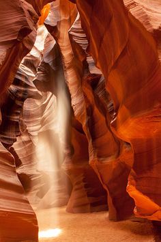 a narrow slot in the side of a canyon with a waterfall coming out of it