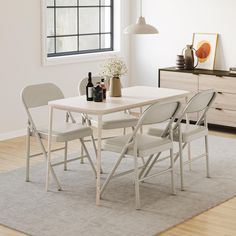 a white table and chairs in a room with a rug on the floor next to it