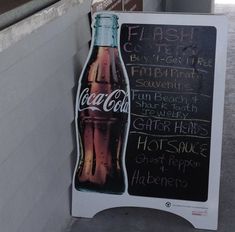 there is a sign that has been placed on the wall next to a soda bottle