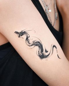 a woman's arm with a black and white tattoo design on her left arm