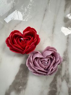 two red and pink flowers sitting on top of a marble table