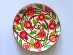 a plate with flowers painted on it sitting on a white table top next to a wall