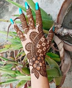 a hand with henna on it and some plants in the backgroung