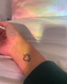 a woman's hand with a small tattoo on her left wrist, resting on a bed