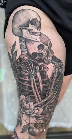 a woman's thigh with a skeleton and flowers on it