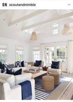 a living room filled with white furniture and blue pillows on top of a wooden table