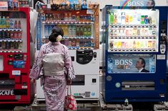 a woman is walking past vending machines