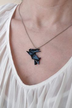 a woman wearing a necklace with an origami bird on it